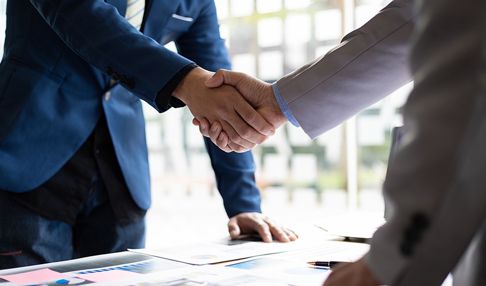 Two attorneys shaking hands above a desk